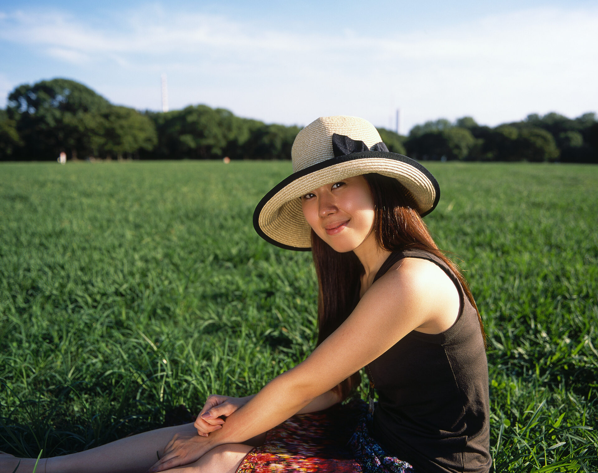 Yuka sitting in a grassy field on a clear day