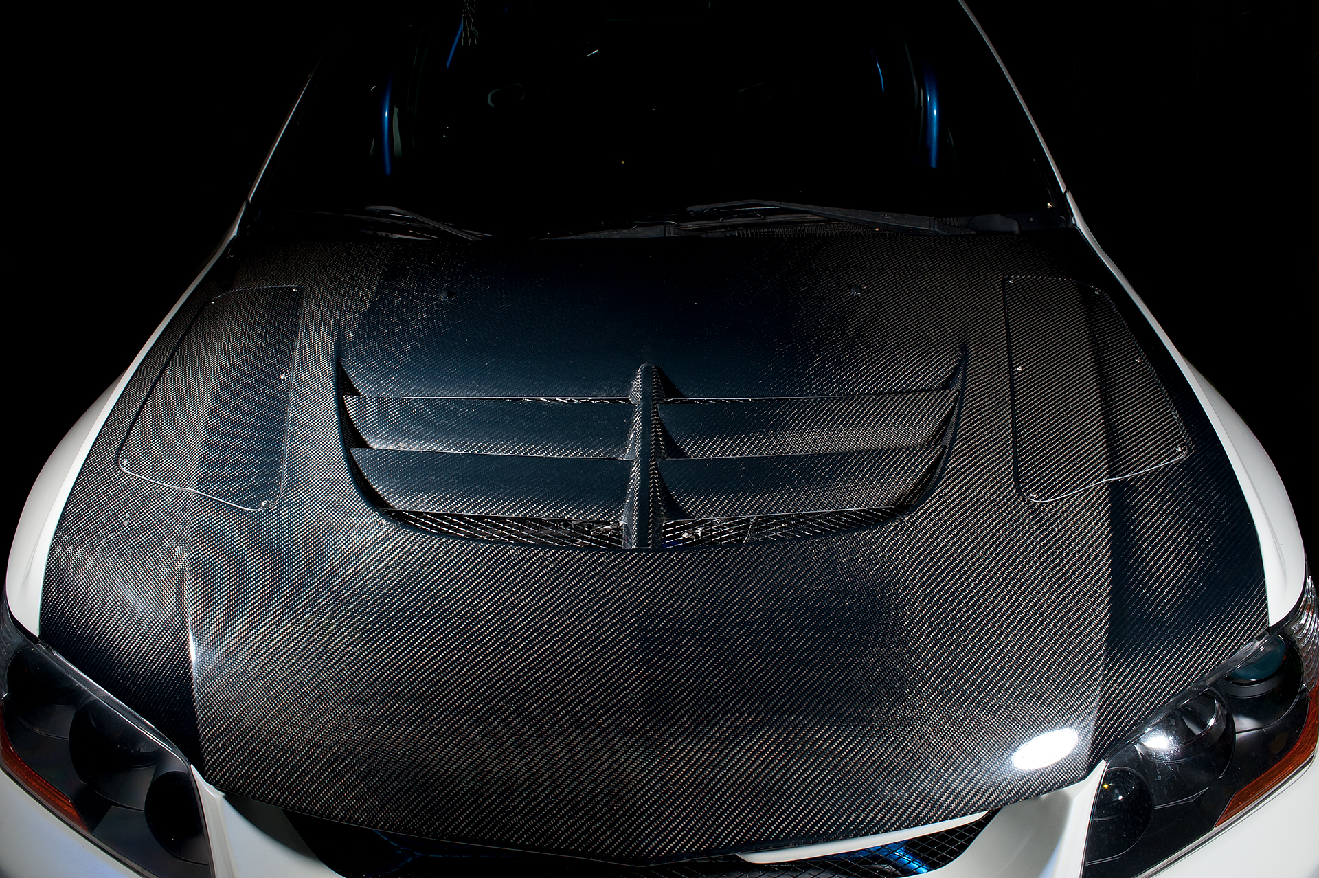 Carbon fiber hood shot of White Mitsubishi Evo IX with Varis body kit