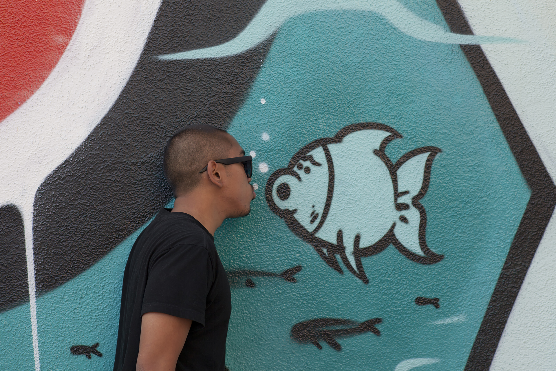 Josh pretends to kiss a fish that is part of a spray painted mural