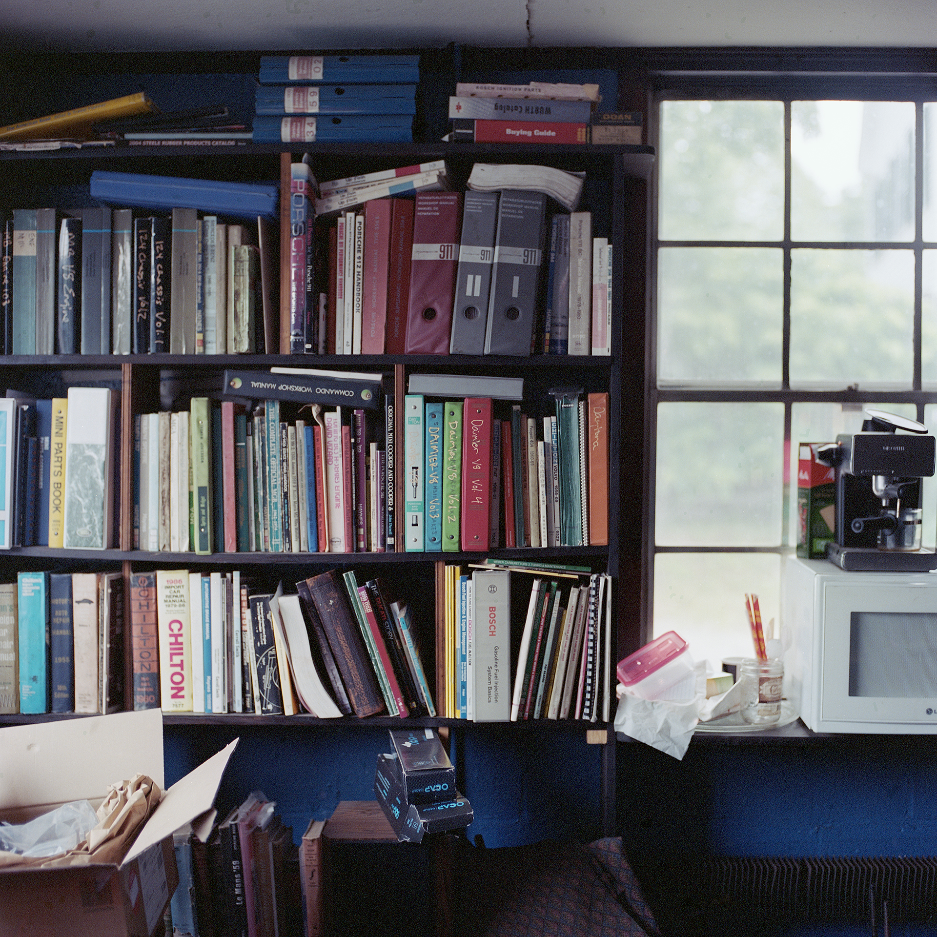 Color photo of book shelf full of car technical manuals at Ava Restoration Services